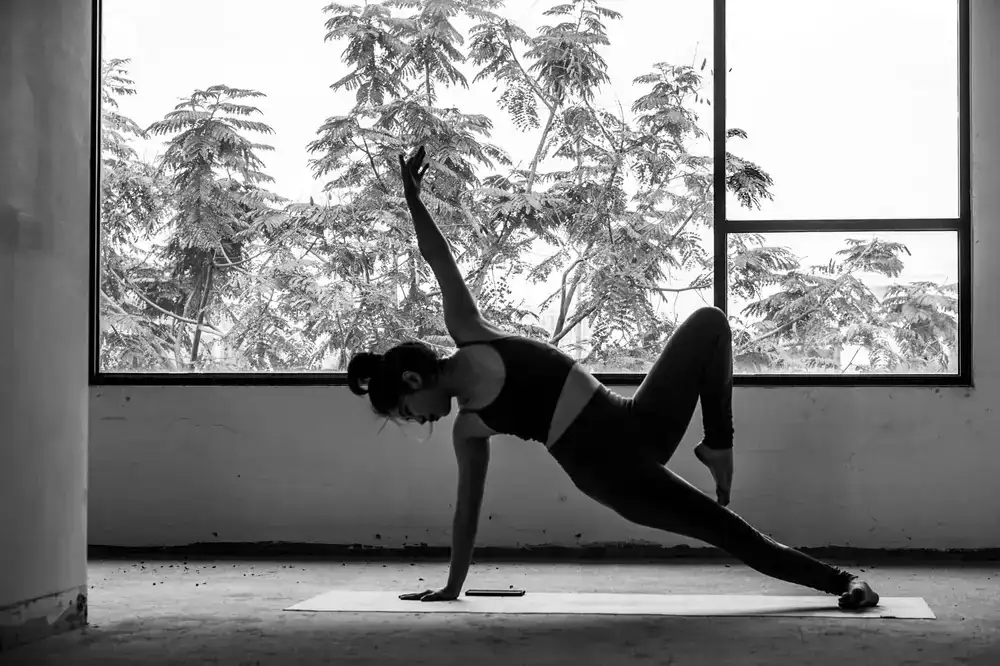 Persona practicando yoga en un entorno luminoso y natural